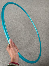Load image into Gallery viewer, a hand holding a teal hula hoop
