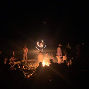 fire performer spinning a fire hoop in front of a bonfire