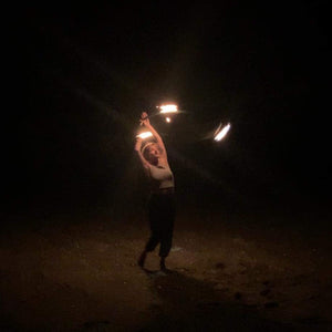 fire performer spinning a burning hula hoop in the dark